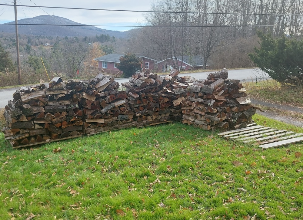 Firewood stacked uncovered on pallets.