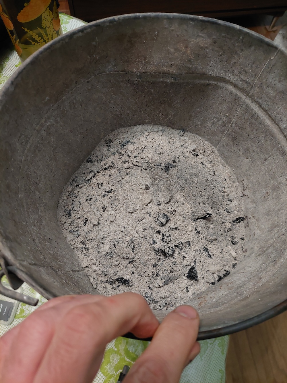 A close up of wood ash in a metal bucket.