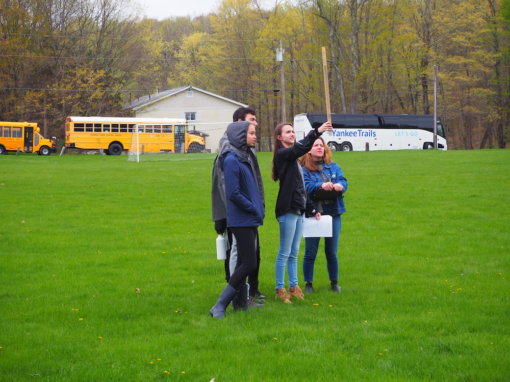 A group of students use a Biltmore stick to estimate tree height.