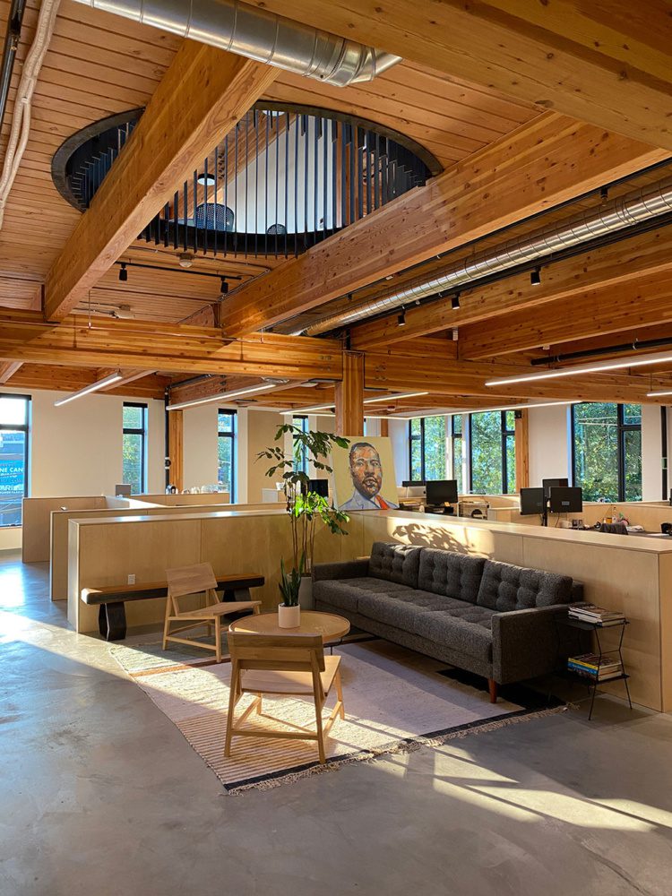 View of an open meeting area blocked off by a half wall with large wood beams and wood ceiling.