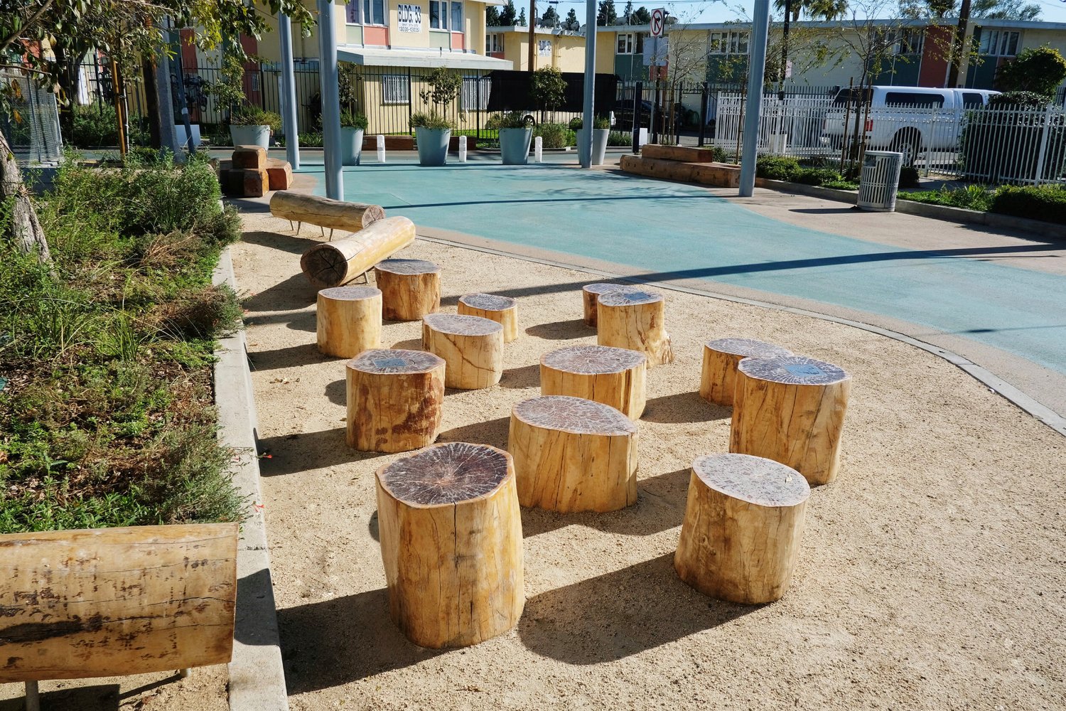 A pastel-colored cul-de-sac with wooden benches and stools beside the street.