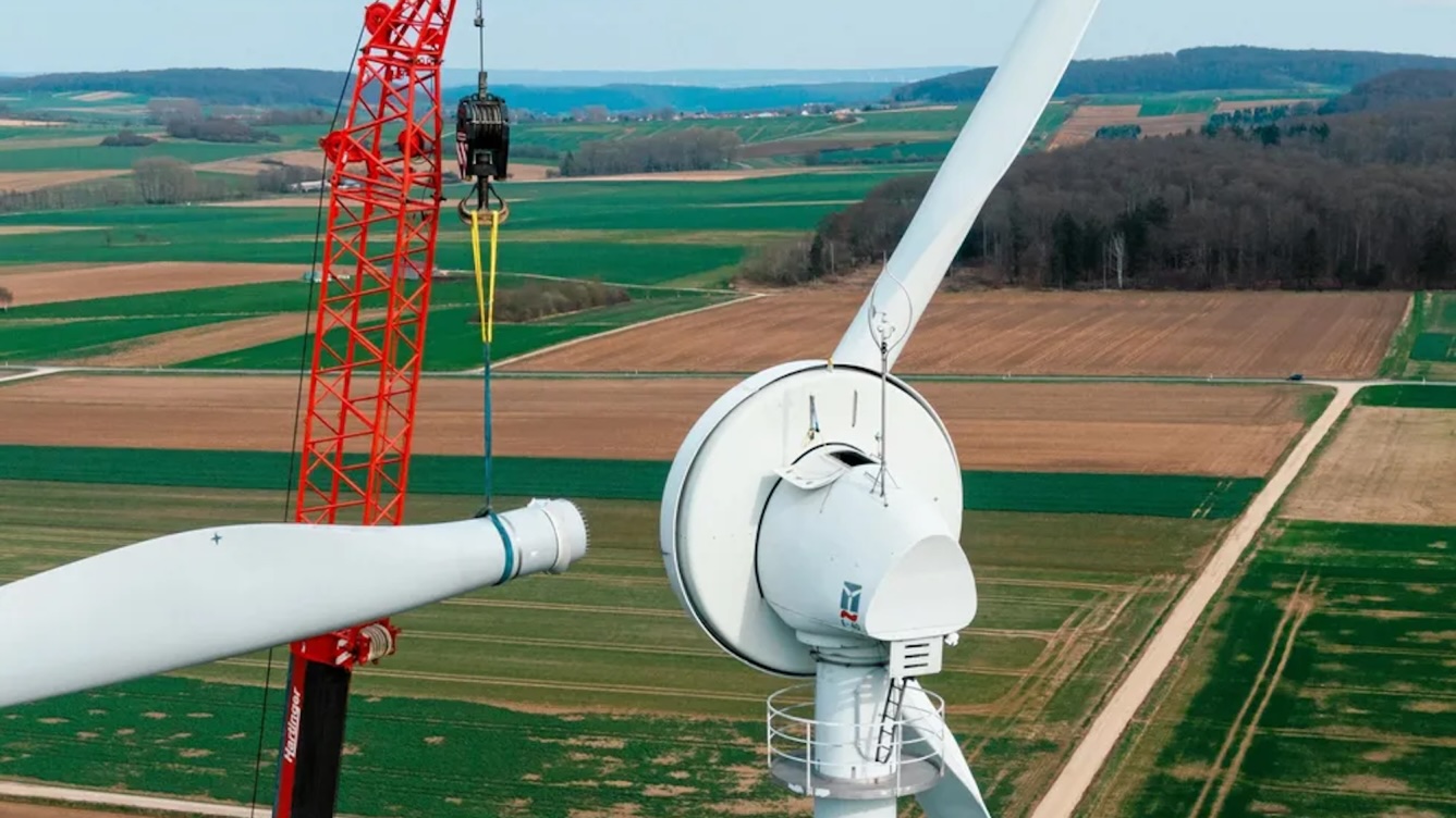 Picture of a wind turbine blade being fastened to a wind turbine tower.