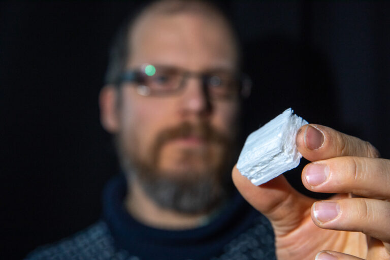 Wood foam. A photo of a man holding a small cube of wood foam in his thumb and index finger.