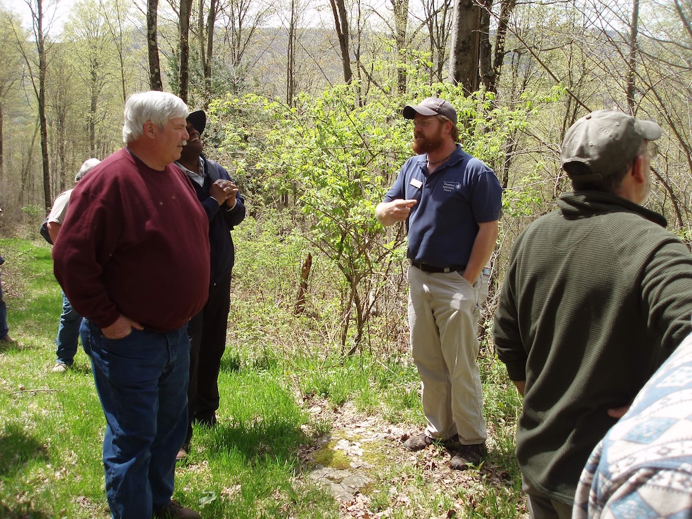 A presenter sharing knowledge at a workshop in the woods in the spring.