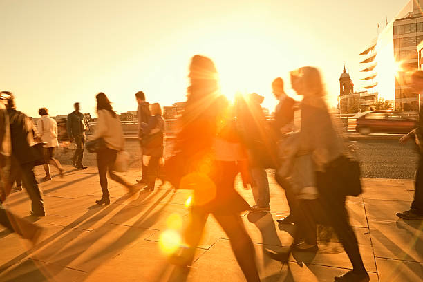Hot summer day in the city. People walking across a hot, treeless, sunlit area in a city.