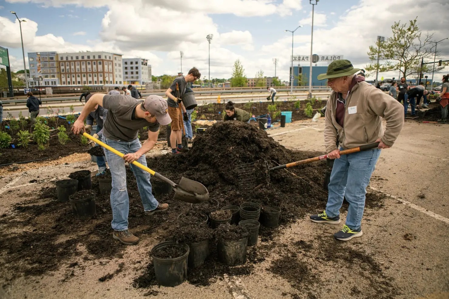 Two men loading containers to enrich the soil with additives from a stockpile.