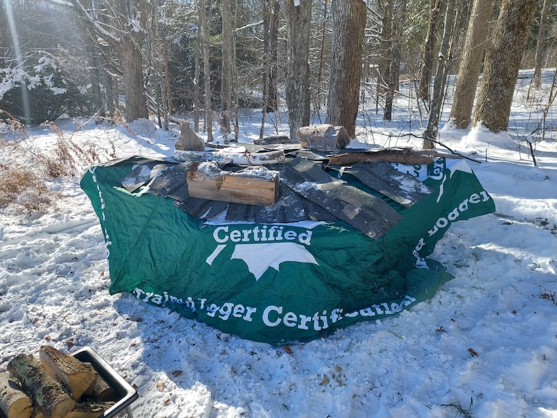 Using the green Trained Logger Certified pop-up tent cover to cover what’s left of the holz hausen.